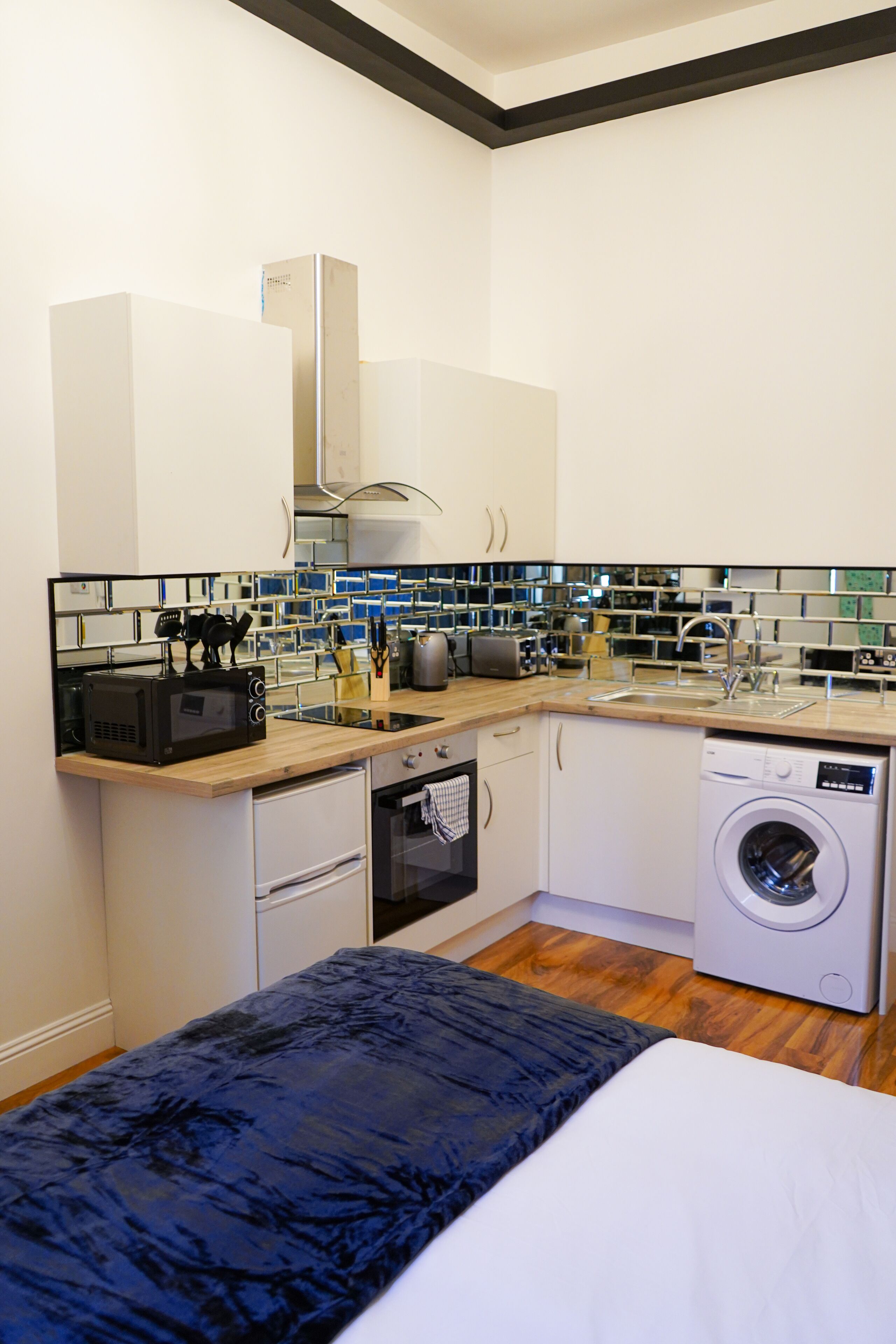 A compact kitchen with a microwave, toaster, sink, and washing machine.