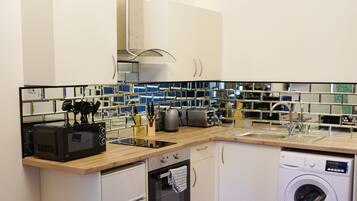 A compact kitchen with a microwave, toaster, sink, and washing machine.