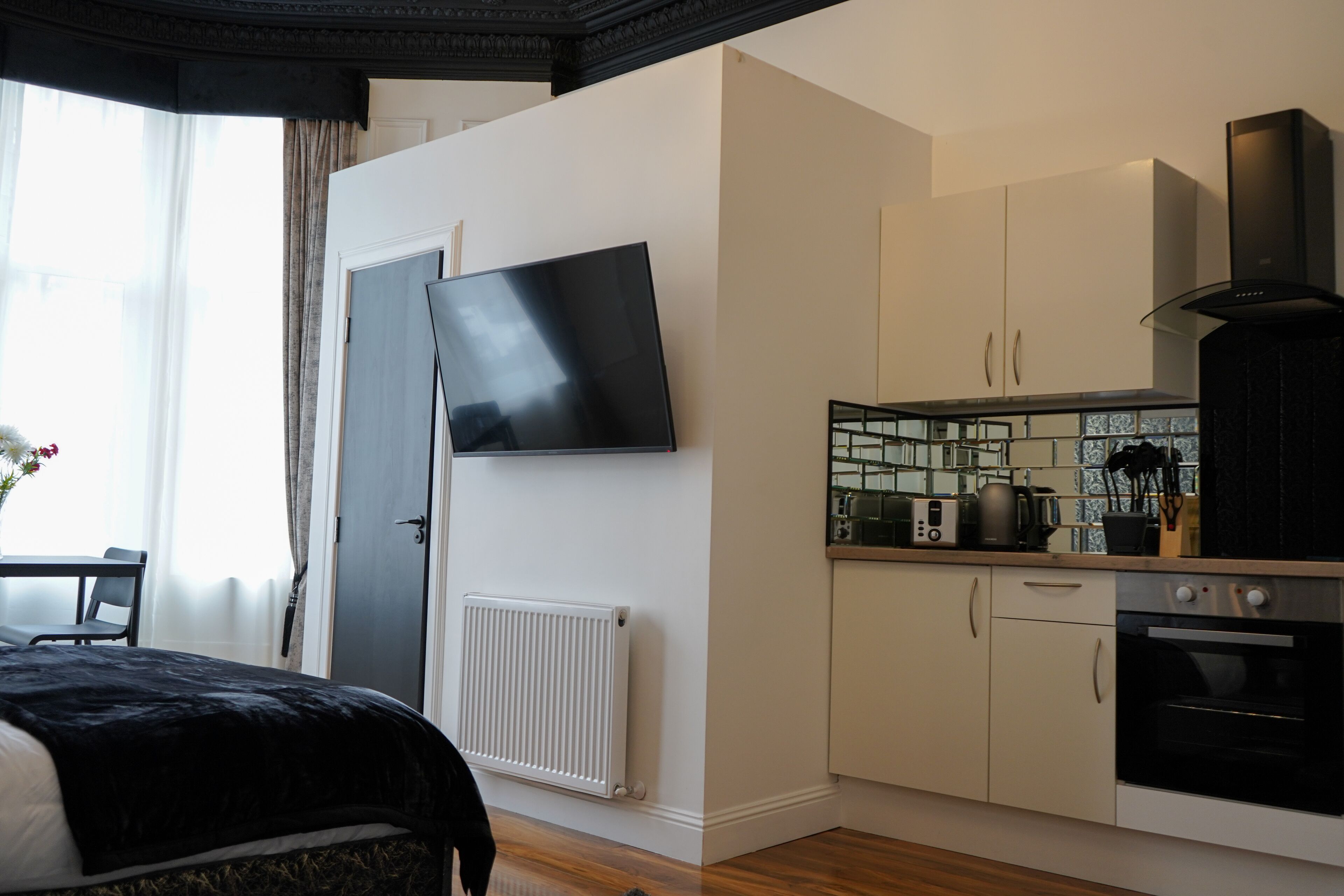 Une chambre d’hôtel moderne équipée d’un lit, d’une télévision à écran plat, d’une kitchenette et offrant une vue sur l’extérieur.