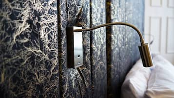 A bathroom with a shower head mounted on a wall with a textured, dark blue and white pattern.