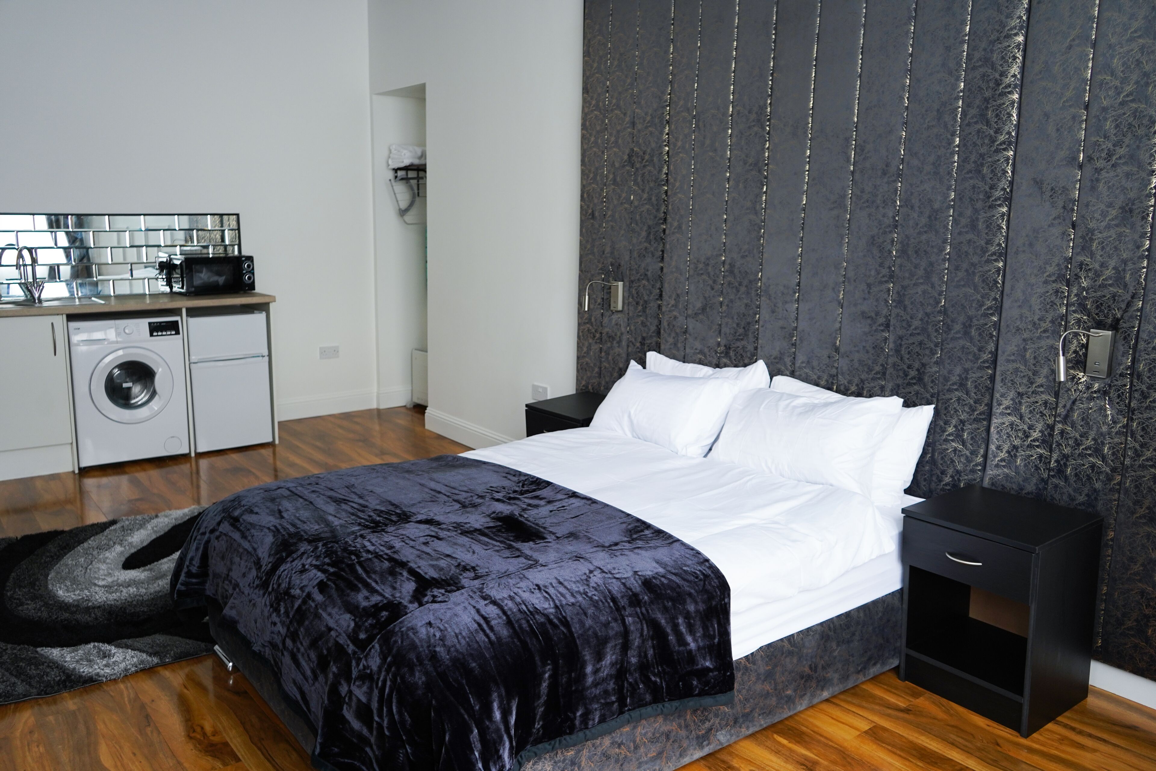 Una camera da letto moderna con un letto grande, una lavatrice e un angolo cottura piccolo.