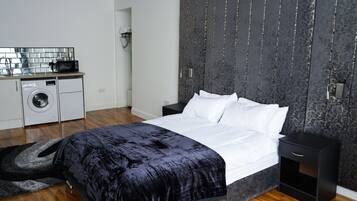 Una camera da letto moderna con un letto grande, una lavatrice e un angolo cottura piccolo.