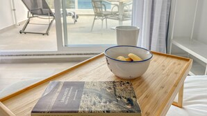 Een kamer met uitzicht op zee, een witte schaal met koekjes op een dienblad, en een boek getiteld 'Lanzarote Guia de Senderismo'.