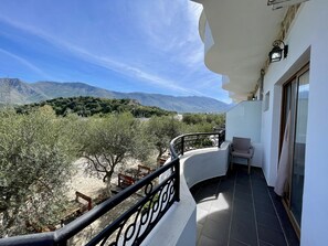 Un balcón con vistas a montañas y olivos.