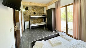 Una habitación con literas, un armario, un televisor y una pared de piedra.
