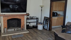 A living room with a fireplace, a television, a ceiling fan, and a coffee maker. - Hidden Gem in Cortland (Cortland)