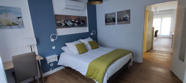 Une chambre à coucher avec un lit, une table de chevet, une lampe et des œuvres d’art murales.