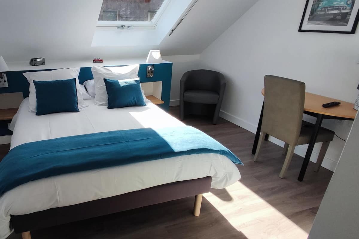 Een moderne slaapkamer met een bed, nachtkastjes, een bureau en een stoel.