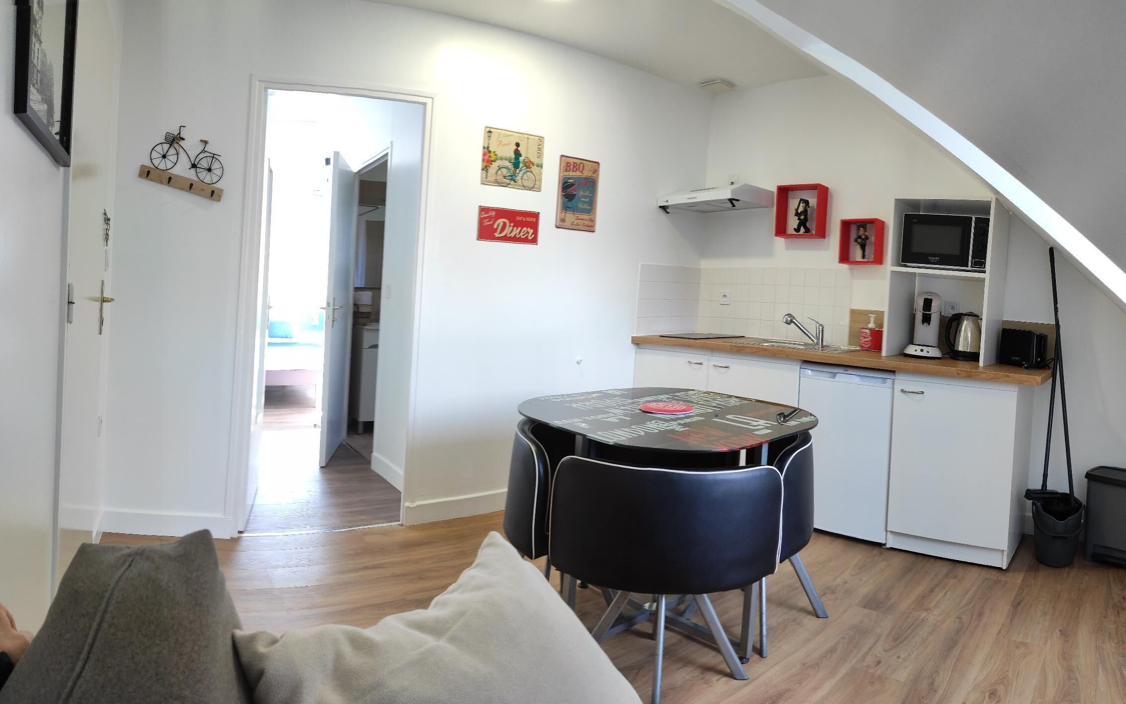 A compact kitchen with a dining table and chairs, a microwave, and a sink.