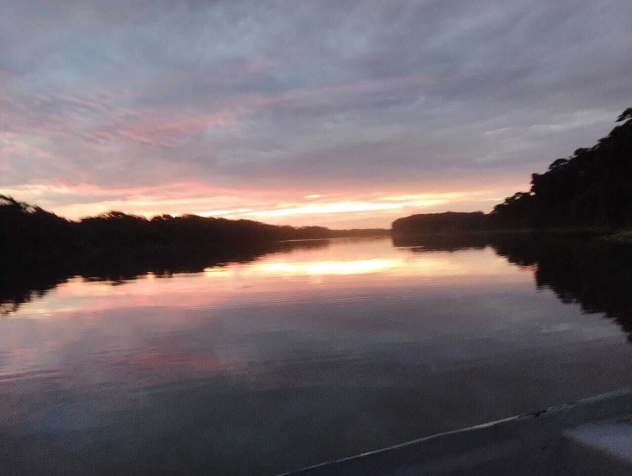 Un río tranquilo al atardecer con árboles a ambos lados.