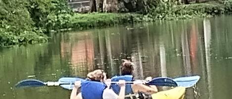 A yellow kayak with two people paddling on a calm body of water.