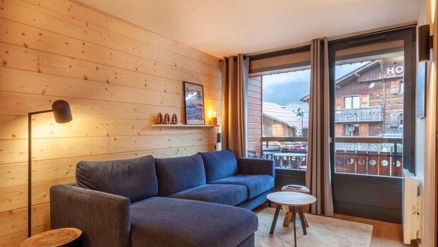 A cozy living room with a blue sofa, a small round table, and a floor lamp. - 190m from ski slopes, 1st floor, balcony, tv, ski locker, 39m², Morzine (Morzine)