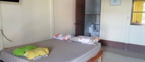 A bedroom with a bed, pillows, and a green and yellow blanket.