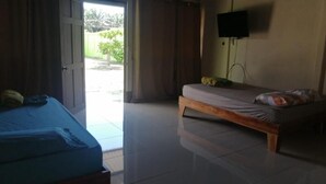 A room with a bed, a television mounted on the wall, and a door leading to an outdoor area. - Cabinas Lawson (Puerto Jiménez)