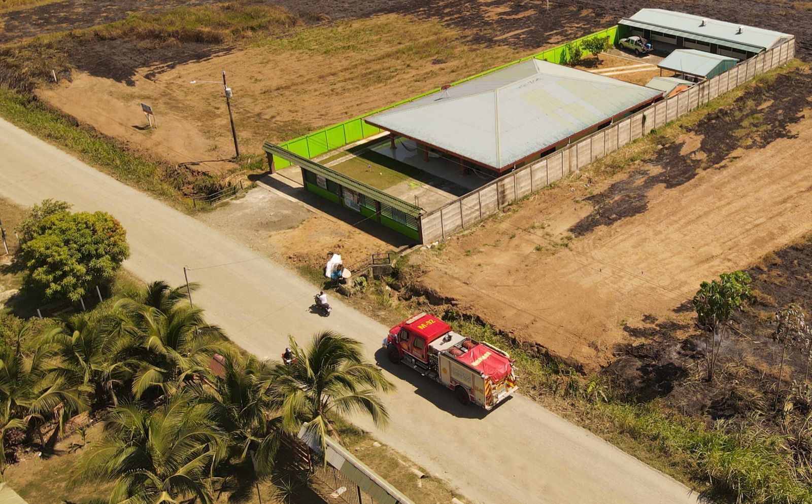 An aerial view of a building with a green roof and a fenced area.