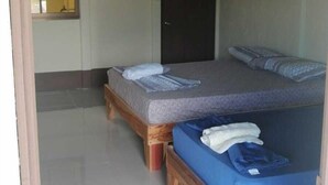 A room with two wooden beds, a dark door, a framed picture on the wall, and a window with a view. - Cabinas Lawson (Puerto Jiménez)