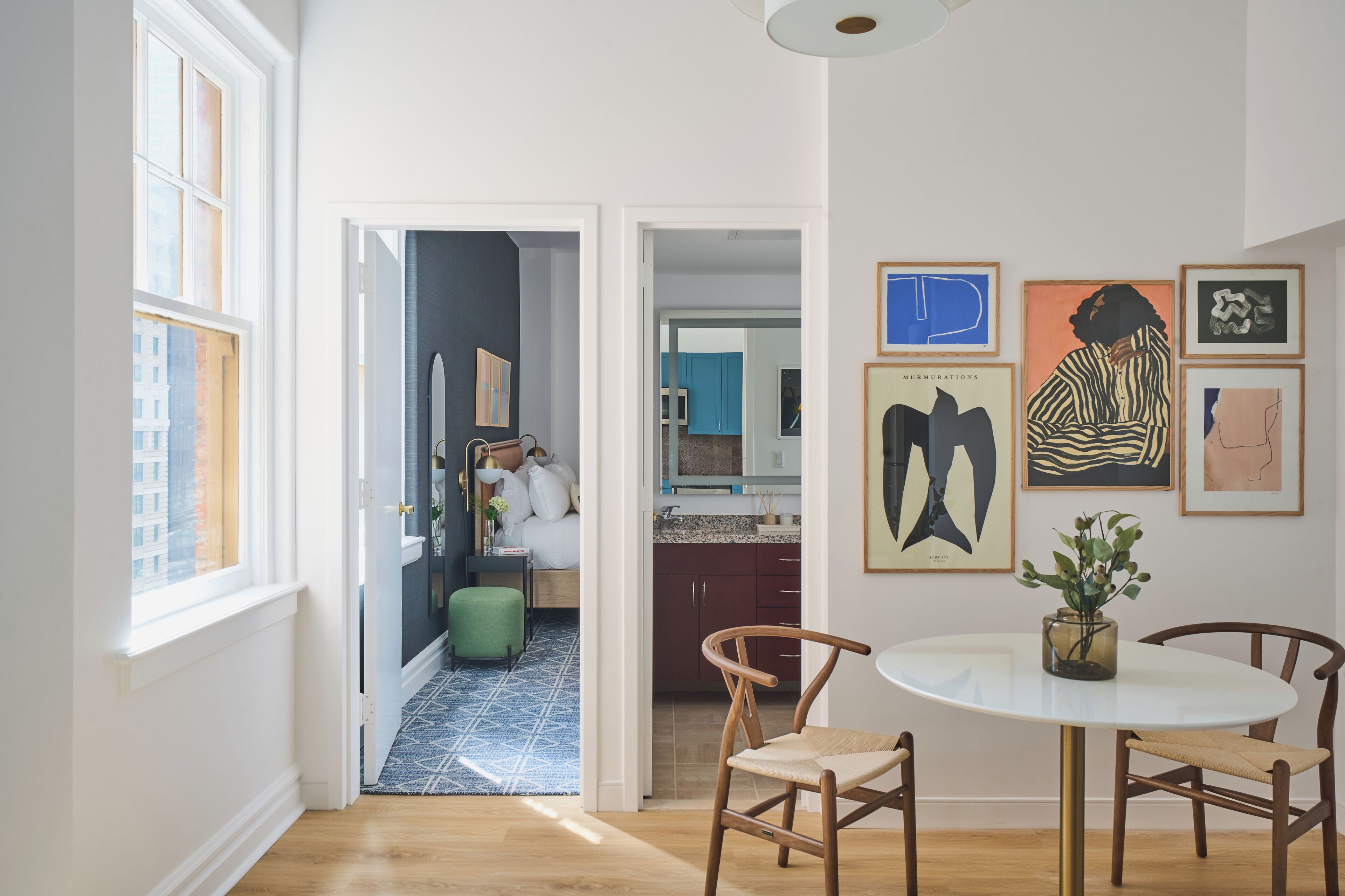 A modern kitchen with dark cabinets, a white countertop, and a view into the dining area.