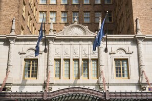 A building with a classical architectural style, featuring a central pediment, symmetrical windows, and two flags.
