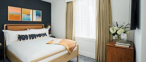 Una habitación de hotel con cama, mesita de noche, televisión y ventana con cortinas.