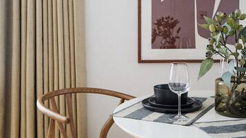 A dining area with a round table, a chair, a wine glass, and a framed artwork on the wall.