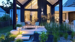 A modern house with a covered patio, outdoor seating, and a fire pit. - Superbe Villa Piscine Intérieure (Combrit)