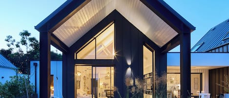 A modern house with a covered patio, outdoor seating, and a fire pit.