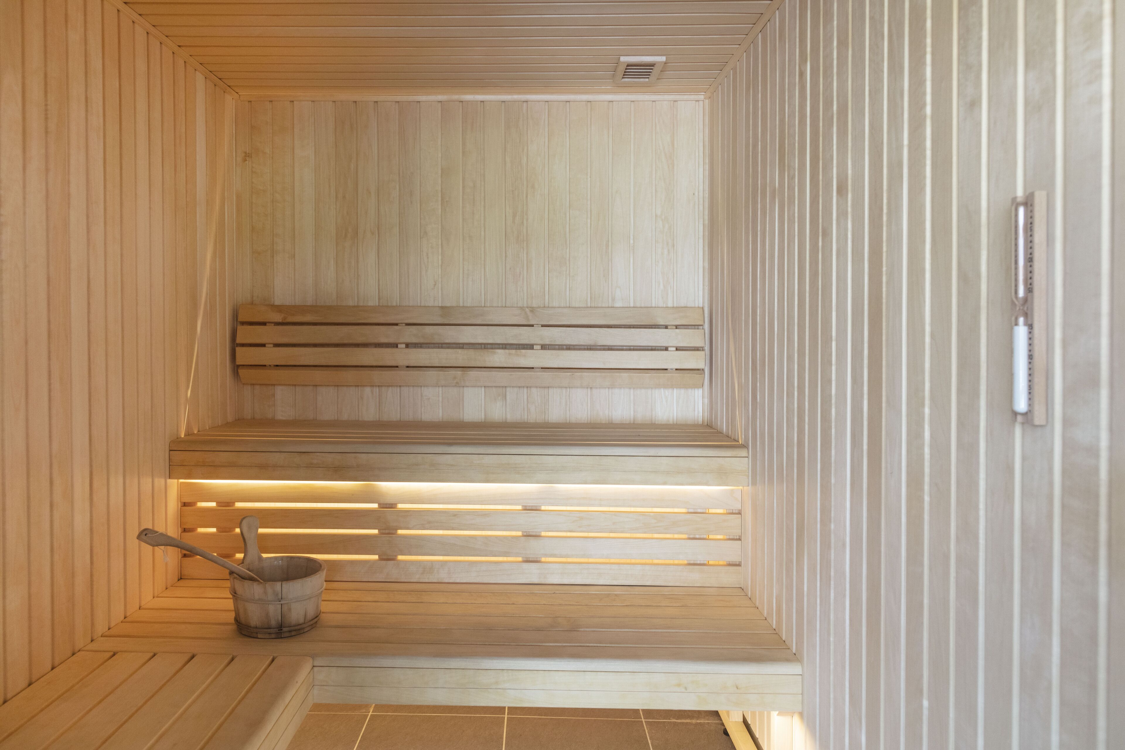 Eine Sauna mit Holzbänken und einem Eimer.