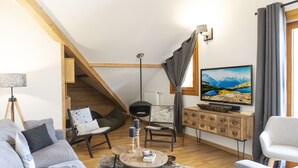 A modern living room with a wooden staircase, a television, and a cozy seating area. - TERRESENS - Les Edelweiss (Vaujany)