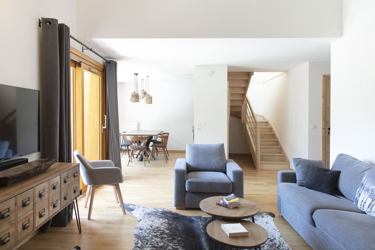 A modern living room with a sofa, armchairs, a coffee table, and a TV on a wooden cabinet.