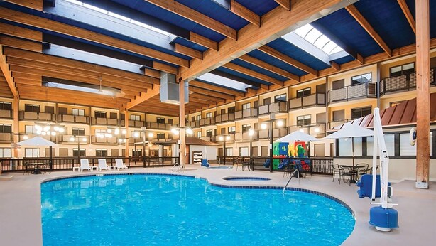 An indoor swimming pool with wooden beams and multiple balconies. - The Eddie Hotel Gillette (Gillette)