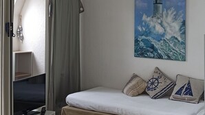 A room with a bed, a TV, and a painting of a lighthouse. - "koantig" Maison/site Exceptionnel, Tregastel,perros Guirec, Trébeurden,calme, (Pleumeur bodou)