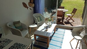 A sunlit patio with wicker furniture, a glass table, and a view of a grassy area. - "koantig" Maison/site Exceptionnel, Tregastel,perros Guirec, Trébeurden,calme, (Pleumeur bodou)