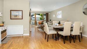 Een moderne eetruimte met een houten vloer, een eettafel met stoelen en een uitzicht door een glazen deur op een terras.