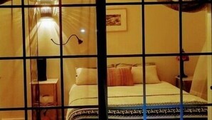 Une chambre avec un lit, une table de chevet et une lampe.