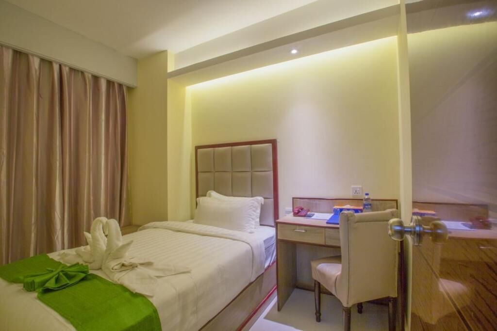 A hotel room with a bed, a desk, and a chair.