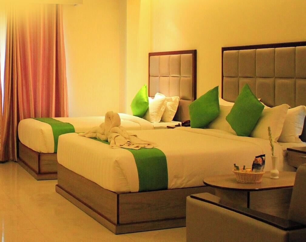 A hotel room with two beds, a small desk, and a chair.
