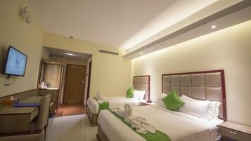 A hotel room with two beds, a desk, a chair, and a television.