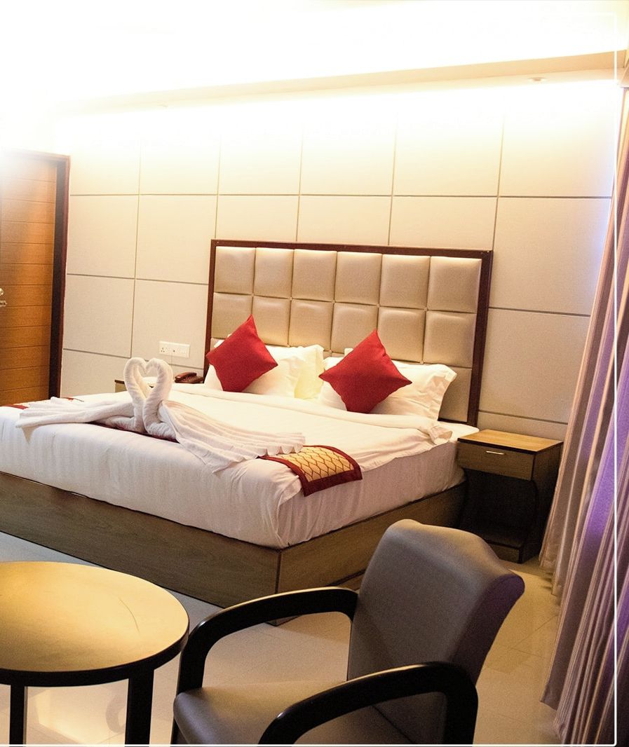 A hotel room with a bed, a bedside table, a chair, and a small round table.