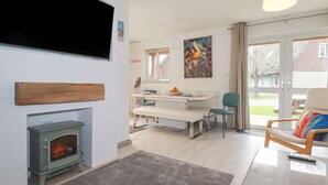 Uma sala de estar moderna com lareira, área de jantar e uma grande janela com vista para o exterior.