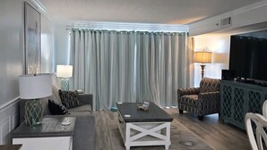 Un salon avec un canapé, des fauteuils, une table basse et un téléviseur.