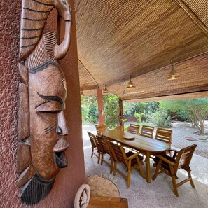 A wooden dining table with chairs, a woven ceiling, and a carved wooden panel. - Résidence du Port Villa N° 98 (Saly)