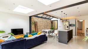 A modern living room with a sofa, TV, and dining area. - Spacious and Charming Brixton Home (London)