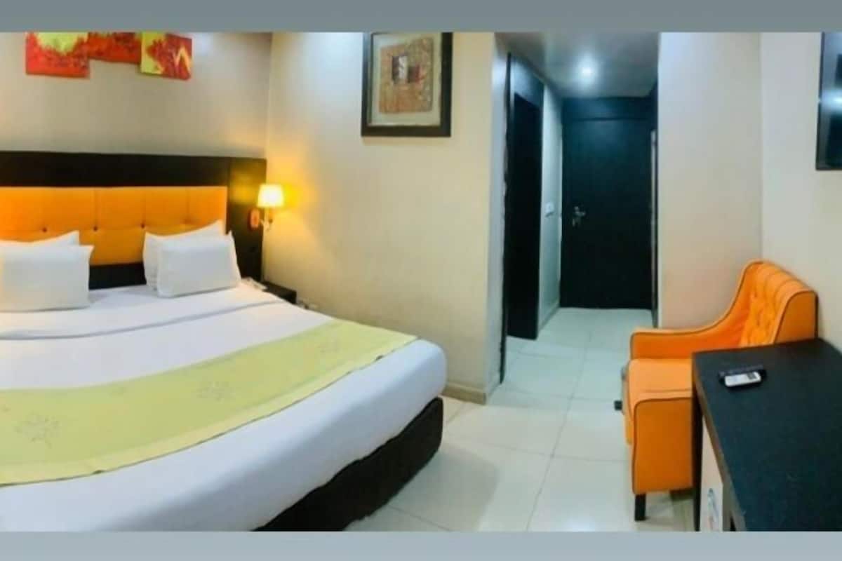 Ein Hotelzimmer mit Bett, Schreibtisch und Stuhl. An der Wand ist ein Fernseher befestigt.