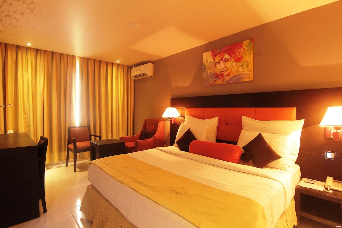 Ein Hotelzimmer mit einem großen Bett, zwei Stühlen, einem Schreibtisch und einem Bild an der Wand.