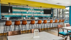 Un ristorante con zona bar, diverse opzioni di posti a sedere tra cui sgabelli da bar e tavoli, e un espositore per il menu.