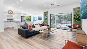 A spacious living area with a black leather sofa, a coffee table, and a glass door leading to a pool. - Seaside Sanctuary at Jupiter Inlet / Dubois Park (Jupiter)