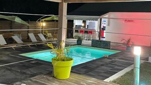 Ein Poolbereich mit Liegestühlen und einer Bar.