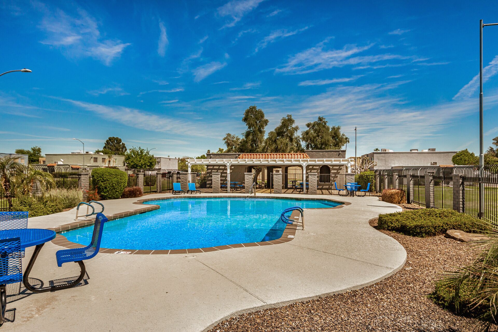 A swimming pool with lounge chairs and a covered patio area.
