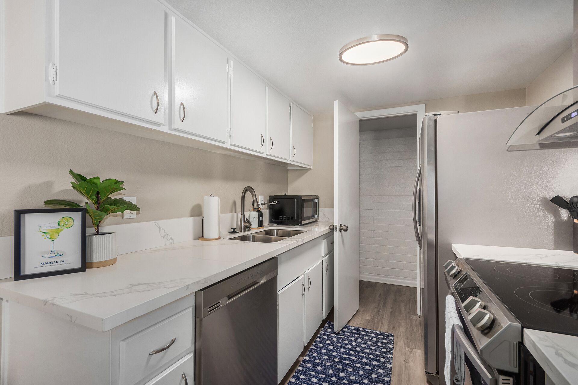 A modern kitchen with white cabinets, a stainless steel dishwasher, a microwave, and a built-in oven.