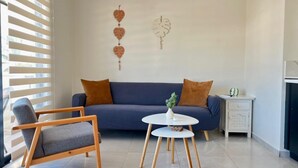 A modern living room with a blue sofa, a wooden chair, and a small white table with a plant.